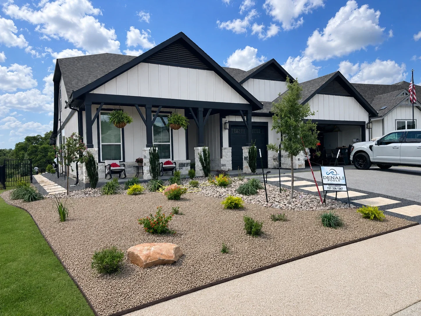 Modern farmhouse home with white siding, black trim, gabled roofs, gravel landscaping, and concrete driveway